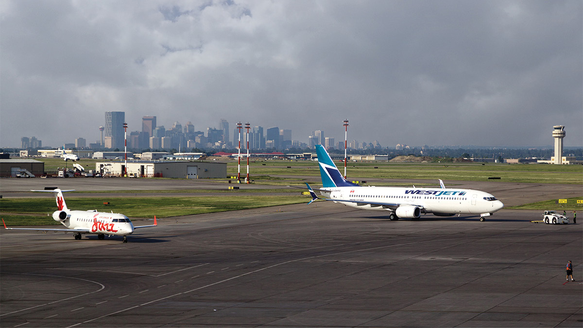 Airplanes parked on runway with cityscape